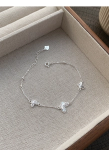 Détail macro du bracelet en argent S925 avec pendentifs papillons et gravure laser brillante