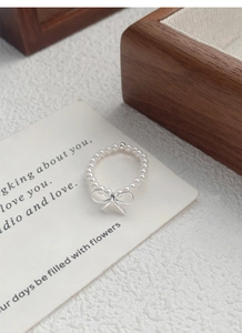 Detail of S925 silver bow pendant on elastic pearl ring with elegant luster