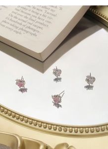 Gros plan de boucles d'oreilles cœur argentées avec pierres roses et blanches sur miroir