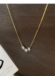 Détail du pendentif en or à trois diamants avec zircons ronds sur chaîne fine