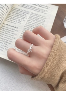 Detail of S925 silver bow ring with small pearls on woman wearing a knitted sweater