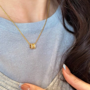 Collier à pendentif barillet doré élégant avec filigrane détaillé sur une chaîne tissée