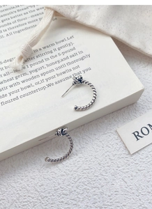 Macro shot of S925 sterling silver rope twist knot stud earrings on vintage book page