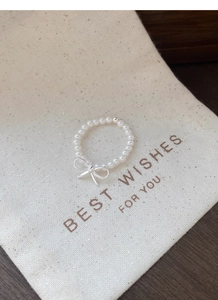 Detailed close-up of S925 sterling silver pearl bow ring on a minimalist linen pouch