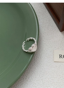 Detail view of S925 sterling silver heart ring with hammer-textured surface on ceramic plate