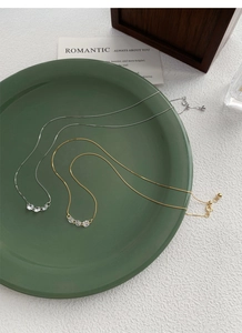 Gros plan de colliers en argent S925 et or avec zircons sur une assiette en céramique