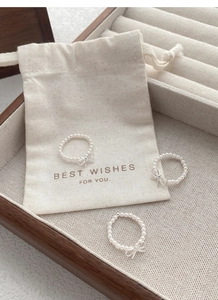 Detailed view of three pearl rings with silver bows on a textured jewelry pouch