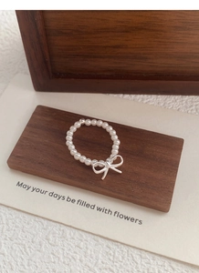 Detailed macro view of S925 sterling silver bow charm on elastic pearl bead ring