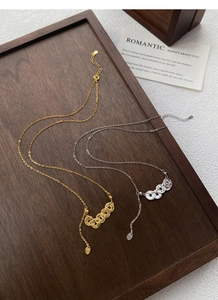 Detailed close-up of S925 sterling silver coin necklaces on a dark wooden tray