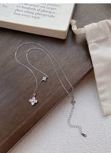 Macro detail of S925 silver clover pendants with zircon inlay on a wooden background