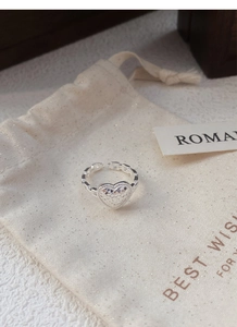 Detailed macro view of S925 sterling silver heart ring with textured finish on a gift pouch