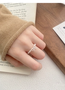 Close-up of S925 silver bow and pearl stretch ring worn on a model's finger