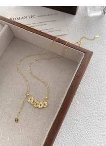 Detail of S925 silver gold necklace with five lucky coin pendants on wood tray