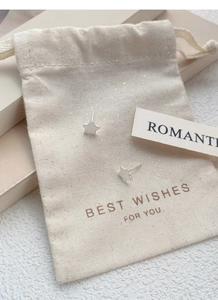 Close-up of S999 silver star stud earrings with textured finish and gift pouch packaging