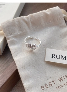 Close-up of S925 silver heart ring with glitter texture on linen jewelry bag