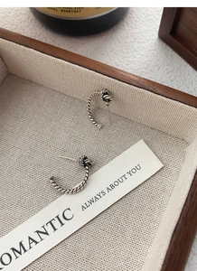 Detailed macro shot of vintage S925 sterling silver twisted knot earrings on linen texture