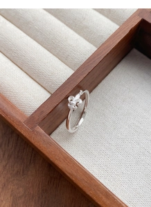 Vue macro détaillée de la bague fleur de lys en argent S925 sur bois rustique et lin
