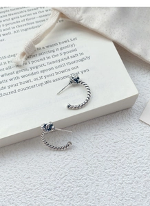 Detailed macro view of S925 sterling silver knot earrings with vintage twisted rope texture