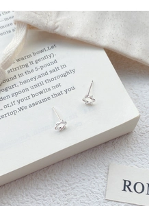 Détail des boucles d'oreilles hexagramme en argent S925 sur une page de livre