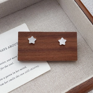 Sparkling S999 sterling silver star stud earrings with beaded edges on a wooden display