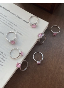 Close-up of 7-piece S925 silver ring set with pink zircons on a rustic wooden background