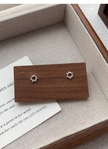 Gros plan de boucles d'oreilles hexagramme en argent sur un support en bois rustique