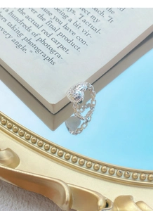 Detail of S925 silver heart ring with honeycomb texture on a blue mirror surface