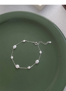 Macro shot of S925 sterling silver frosted round disc bracelet on a green plate
