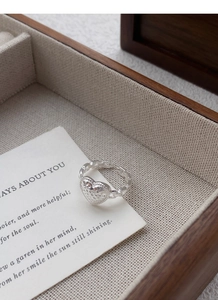 Macro shot of silver heart ring with textured surface in a wooden jewelry box