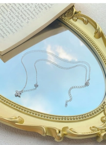Macro detail of S925 silver four-leaf clover necklace with crystals on a mirror reflection