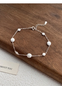 Detail of S925 sterling silver bracelet with frosted round charms on a walnut stand