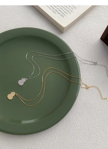 Detailed close-up of gold and silver gourd pendants on a vintage scale textured chain