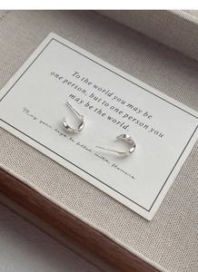 Macro view of S999 silver Mobius twist stud earrings on a vintage poem card
