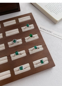 Macro shot of assorted emerald-cut green gemstone rings in a wood jewelry box