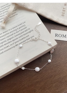 Close-up of S925 sterling silver bracelet with matte round discs on a vintage book