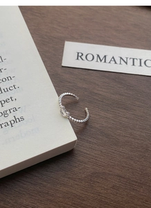 Detailed close-up of a silver bear-themed open ring with bead texture on wooden desk