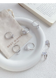 Set of 6 sterling silver rings with various cubic zirconia cuts on a white ceramic plate
