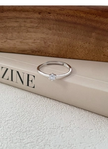 Detail of a six-prong silver ring featuring a round brilliant-cut solitaire diamond