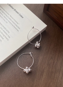 Macro detail of S925 sterling silver hoop earrings with diamond-cut beads in a leaf shape