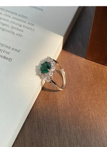 Macro detail of S925 silver emerald ring featuring oval green gemstone with halo diamonds