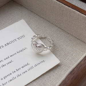 S925 sterling silver heart ring with hammered texture and chain band on a beige fabric