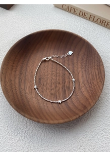 Detail of S925 sterling silver star bracelet with polished charms and engraved hallmark