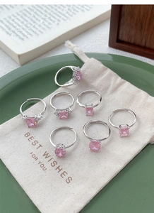 Close-up of S925 silver rings set with pink zircon stones on an elegant gift tray
