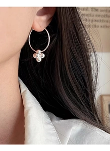 Detail of silver clover-shaped earrings featuring polished bead balls worn on the ear