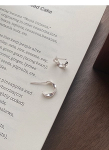 Macro shot of silver Mobius stud earrings on a book page showing a polished twisted design