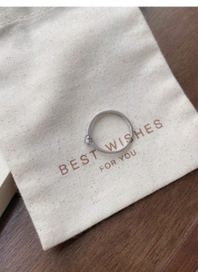 Detail of S999 sterling silver six-prong solitaire ring on a textured fabric jewelry bag