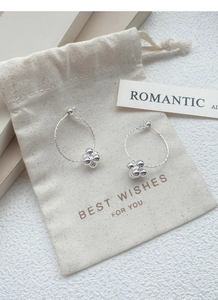 Detail of silver hoop earrings with sparking bead charms on a soft velvet jewelry pouch
