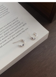 Close-up of S999 sterling silver Mobius twist stud earrings on a book page