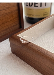 Detailed macro view of S925 sterling silver hollow bear ring on a dark walnut tray