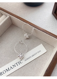 Detailed shot of S925 silver hoop earrings with a beaded flower charm on linen tray